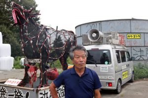 מר יושיזאווה על רקע טנדר המחאה שלו