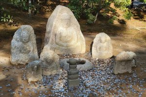 מטבעות שהושלכו אל עבר בודהה חקוק באבן כסגולה למזל טוב