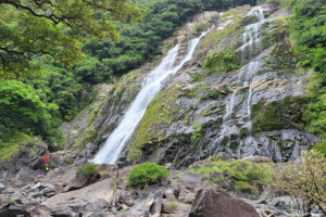 בחורה עומדת לצד מפלי אוקו נו טאקי יקושימה